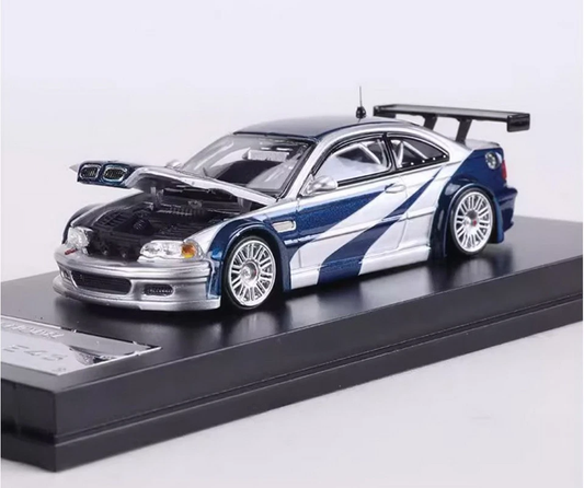 Silver and blue BMW E46 die-cast model with racing graphics, open hood, multi-spoke wheels, rear wing, and black display base